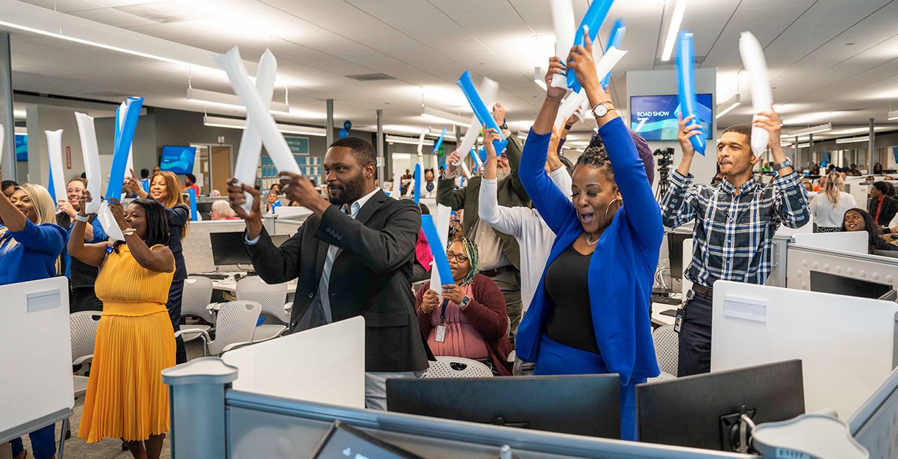 Spectrum employees celebrating an an office event holding balloons over their heads