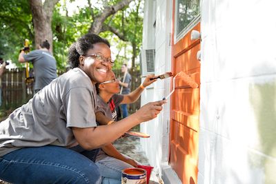 Two women painting a home and smiling